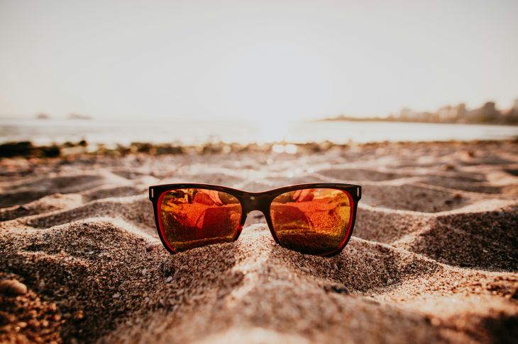 Eine Sonnenbrille liegt am Strand.