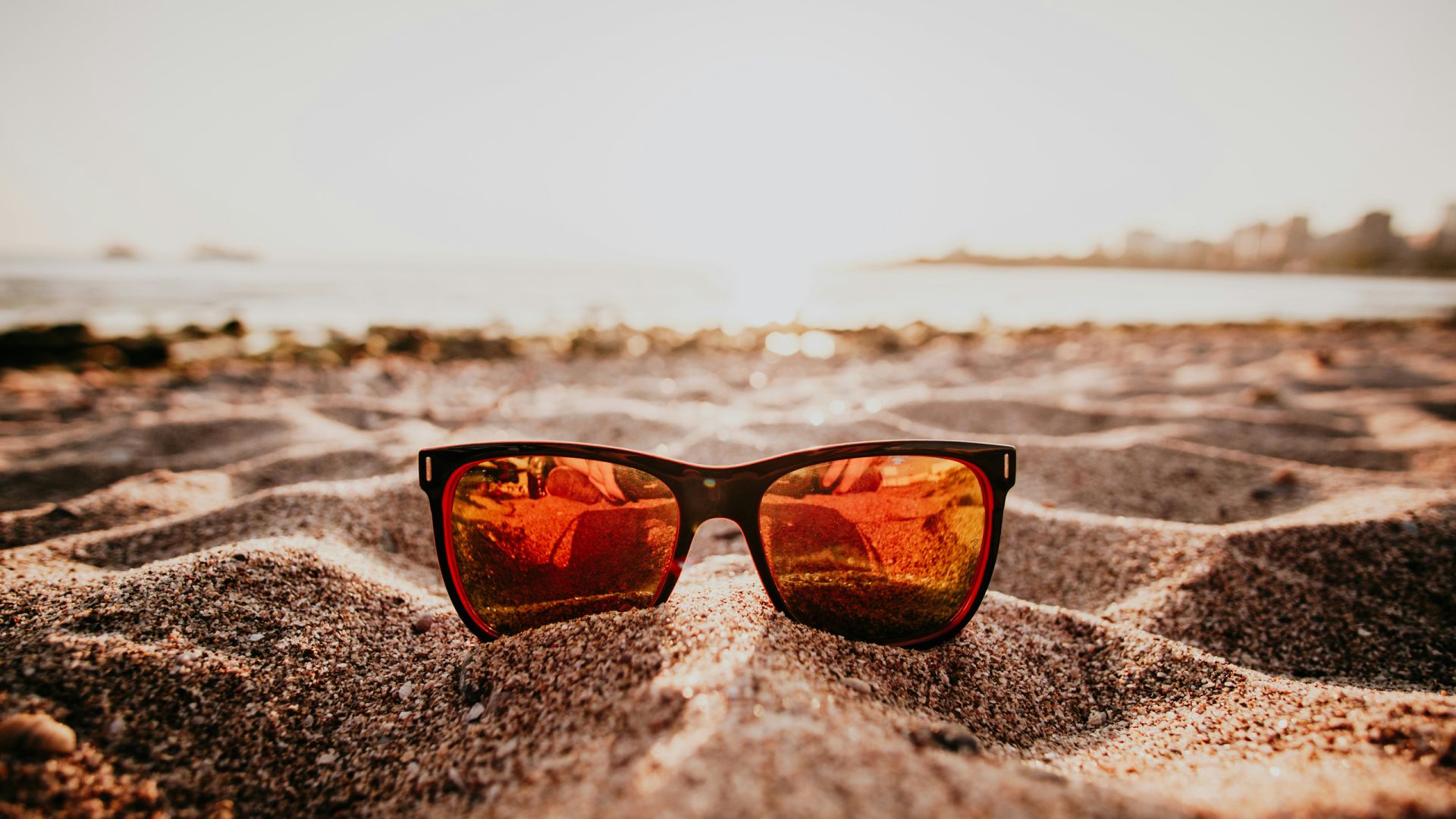 Eine Sonnenbrille liegt am Strand.